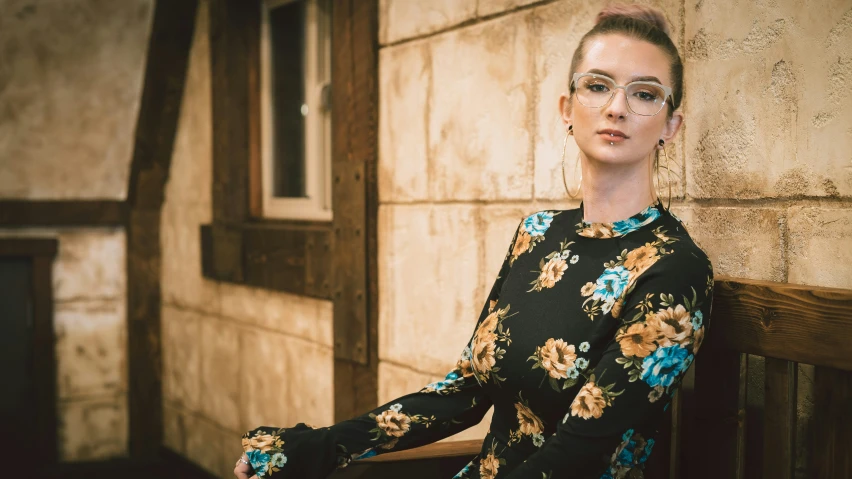 a woman with glasses leans against a wall