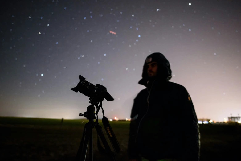 the pographer stands next to his tripod in front of the stars