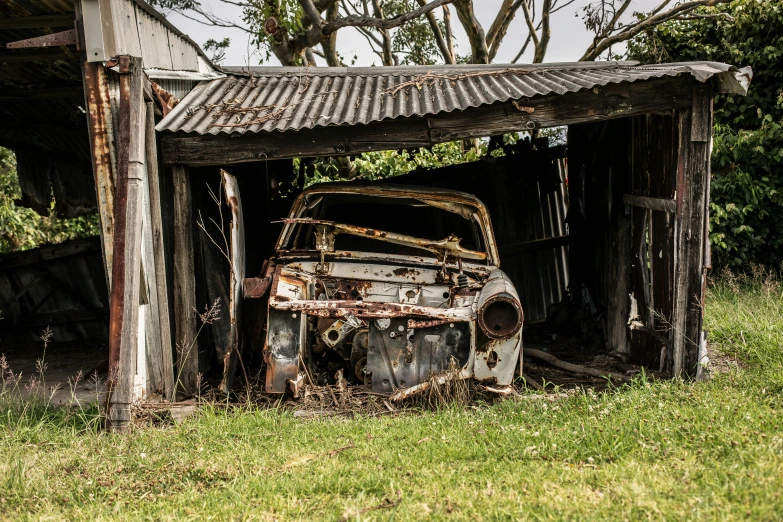 an old run down car is parked under the shelter