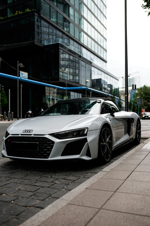 a white car sitting on the side of a road next to tall buildings