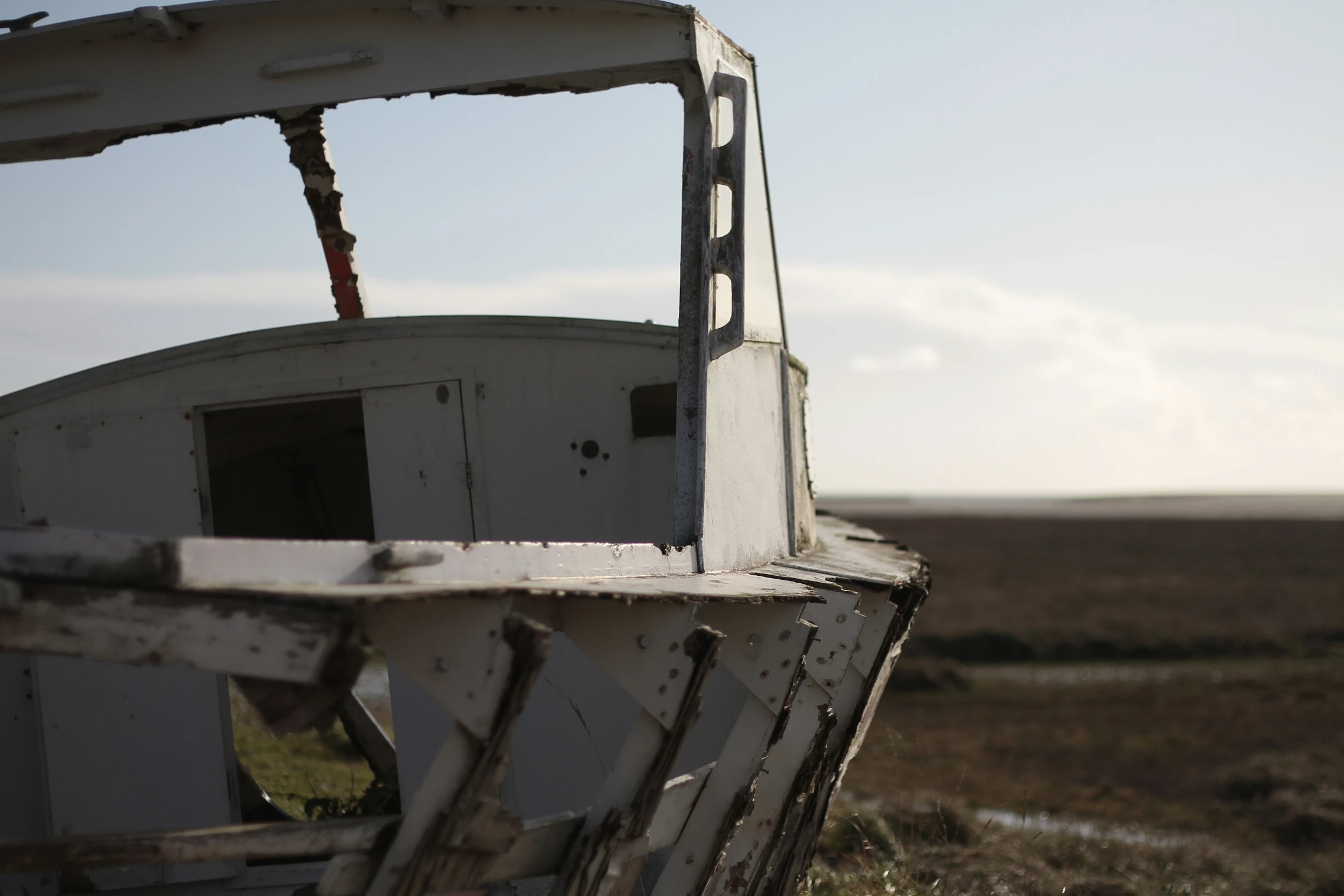 an old, broken out boat in the open field