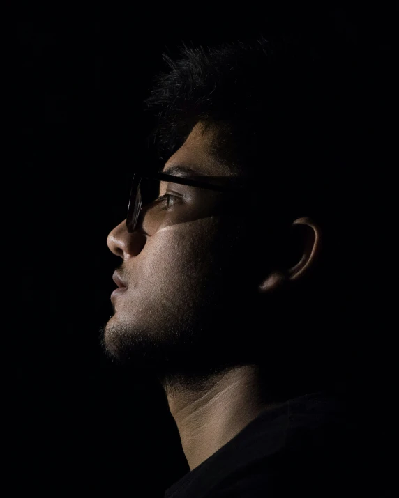 a man in a dark room wearing glasses