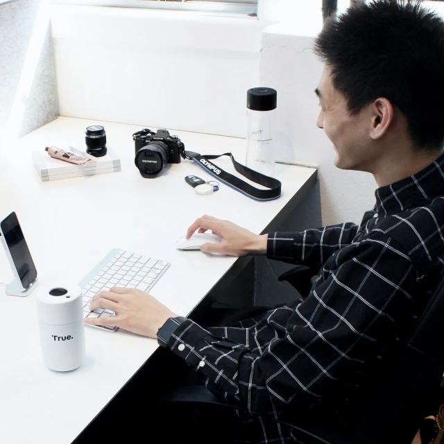 a man sitting at a desk with a laptop and a keyboard in front of him