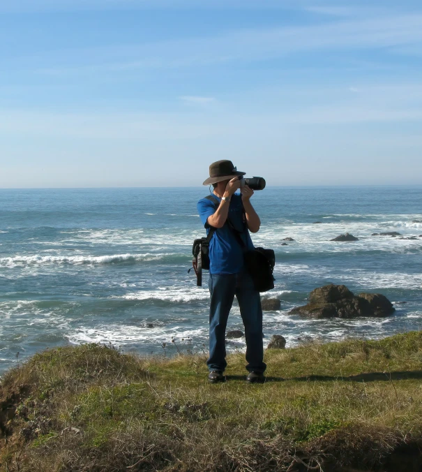 a man standing on top of a cliff next to the ocean