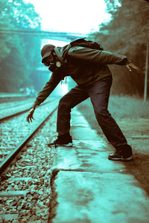 man leaning forward on train tracks with one arm outstretched