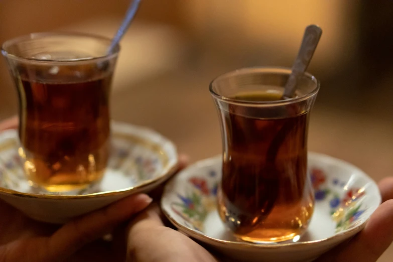 two people holding cups with tea in them