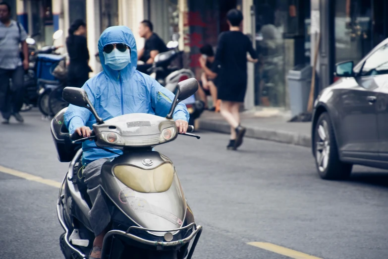 a man riding a scooter on a street near parked cars