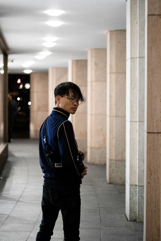 a man standing outside of a building wearing blue clothes