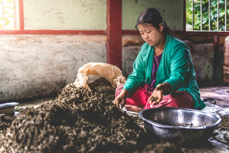 a woman sorting food from the ground into bowls