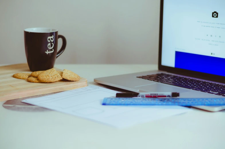 a wooden desk with a laptop and cup on it