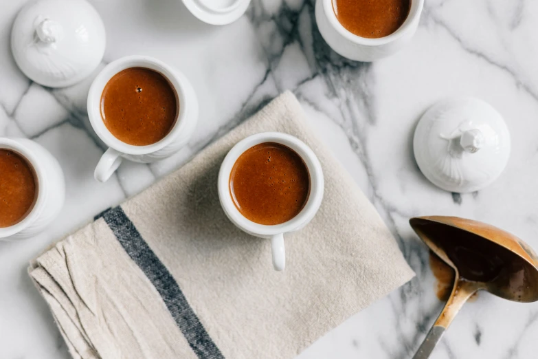 some white cups sitting on top of a counter next to brown spoons