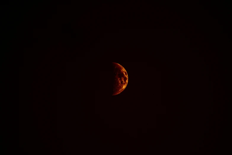 a moon and a dark night sky with a bright red light