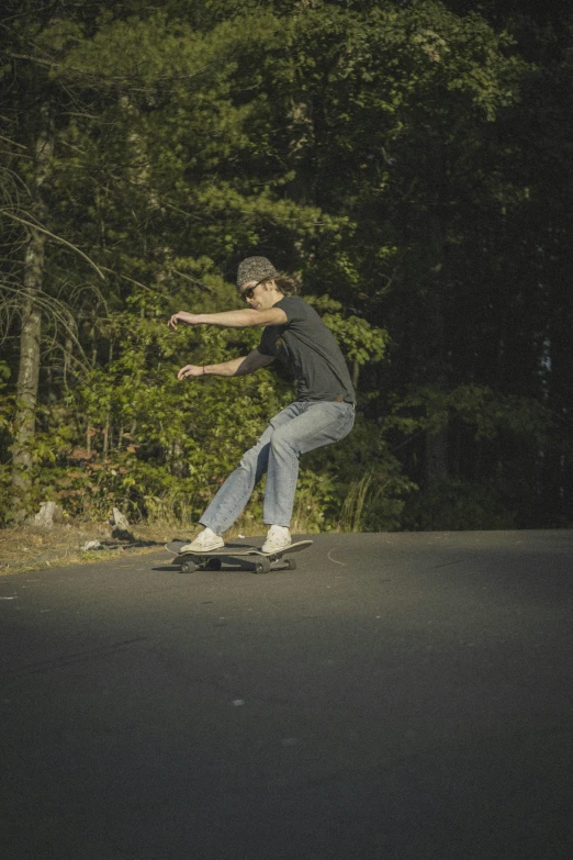 a skateboarder skating down a road in front of trees