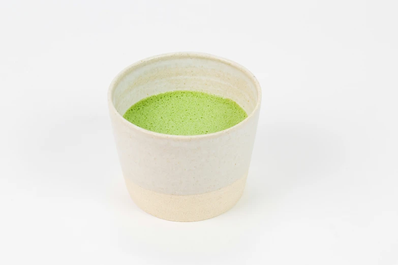 a cup filled with green liquid on a white background