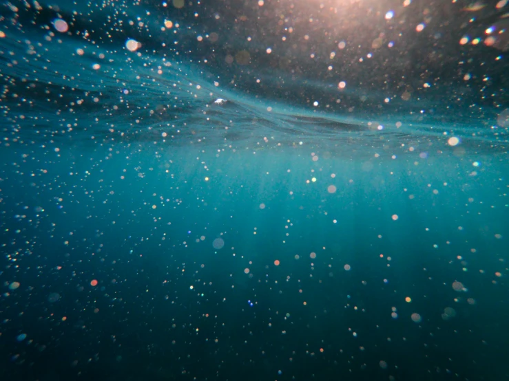 an underwater view of the ocean, with sunlight shining on it