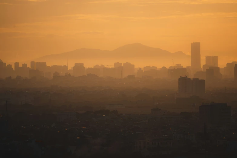 city buildings with the sun low on top and fog in front