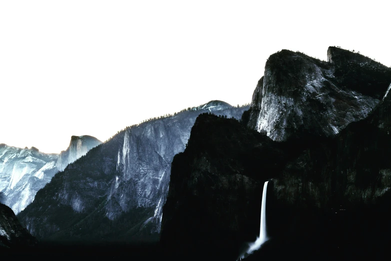 two mountain peaks are in the distance, with a waterfall in the foreground