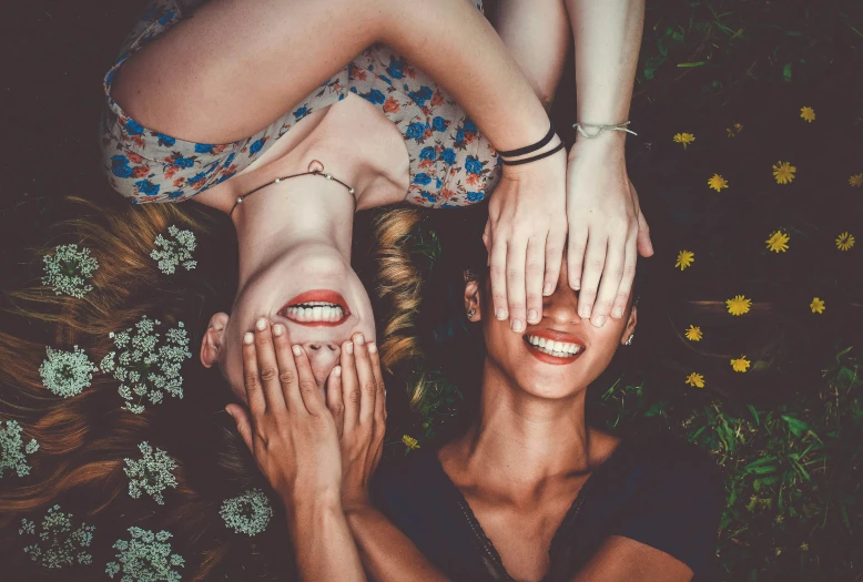 two women standing in the grass with their hands over the woman