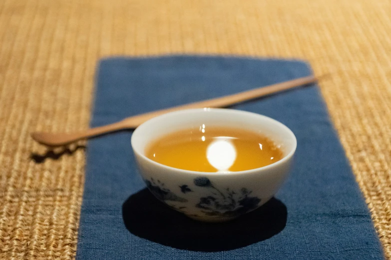 a tea in a white bowl on top of a blue mat