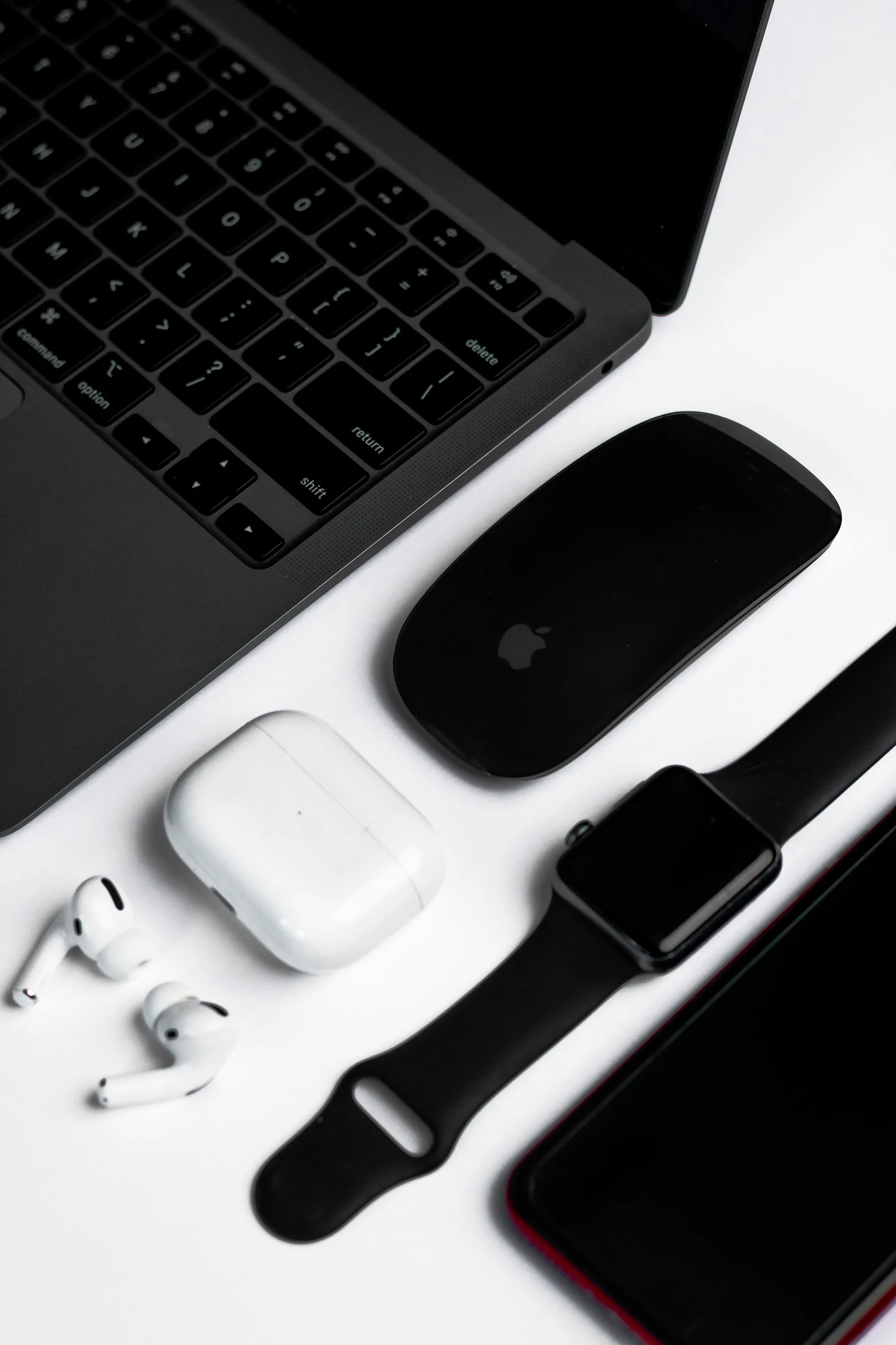 an apple phone, headphones, and earbuds laid out on top of a desk