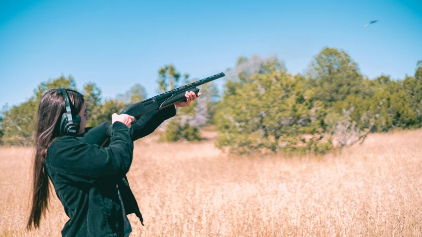 a woman is holding a gun with an odd face