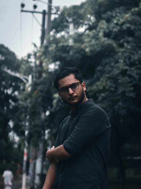 a man in glasses standing on a street corner