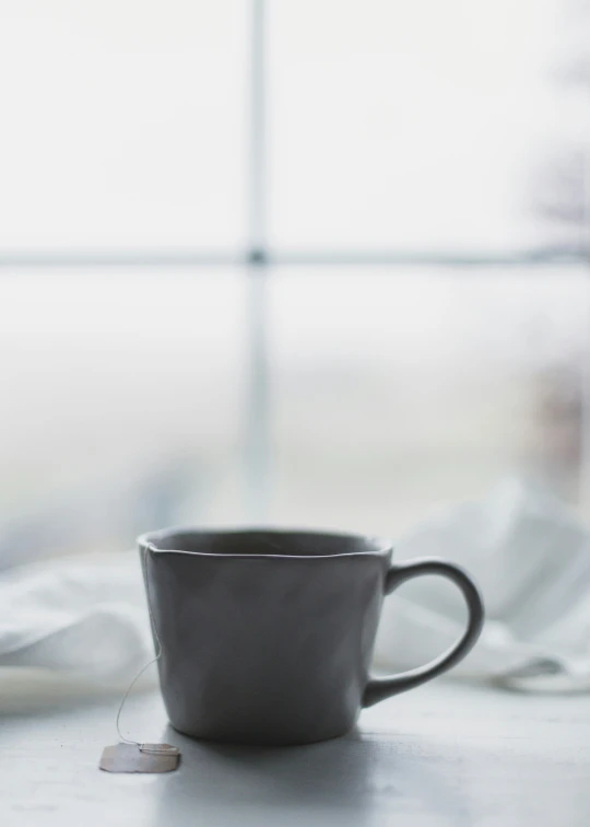 an empty black coffee cup sitting in front of a window