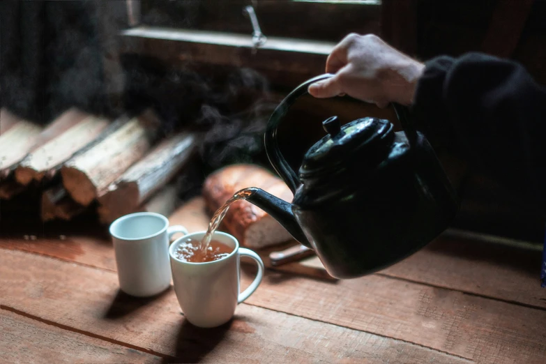 two mugs are being filled with tea and water