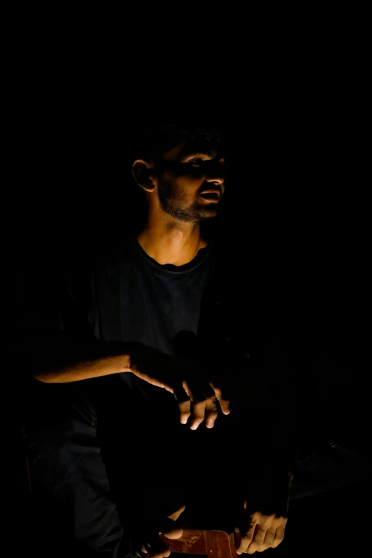 a man sitting in the dark with a knife