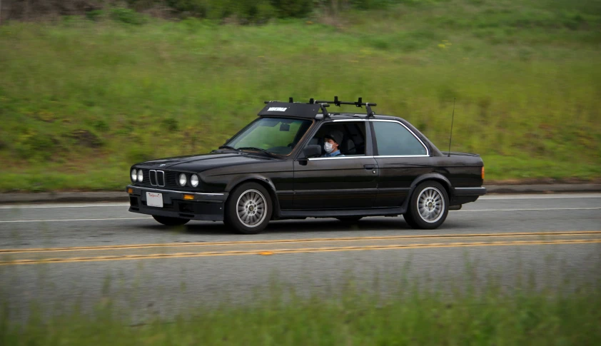 black bmw is going down the road with its roof up