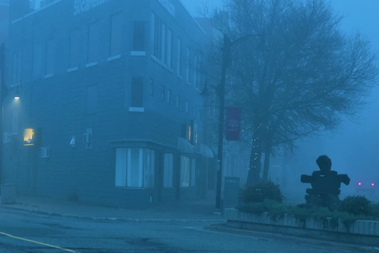 fog is rising up from the corner of an urban street