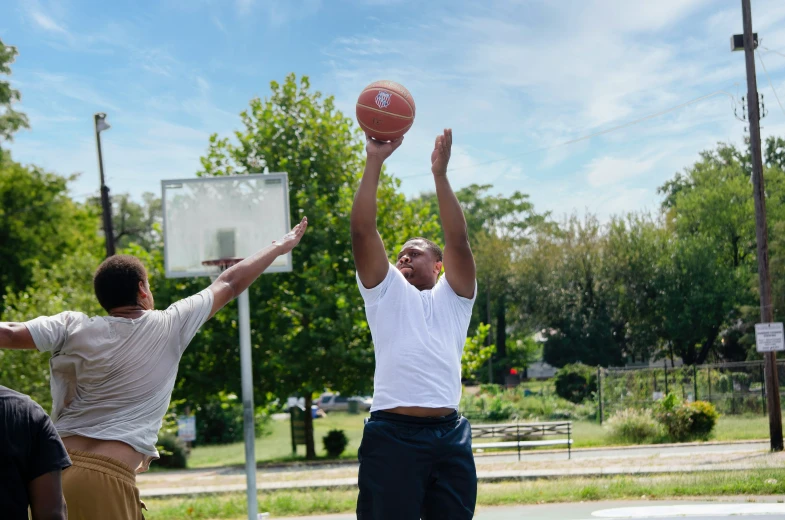 three men play basketball on an outdoor court