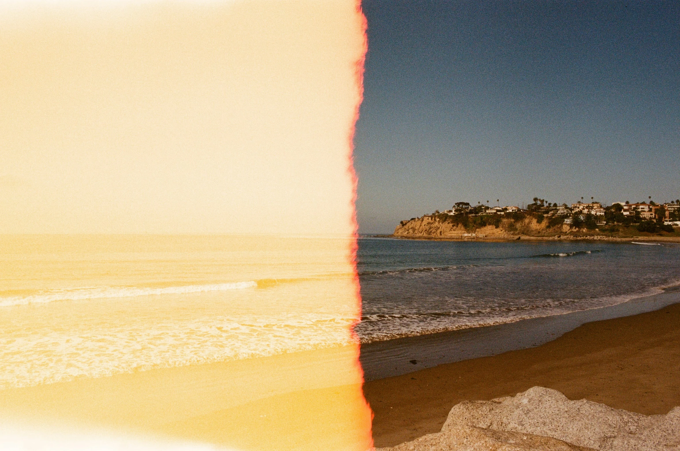 beach scene with buildings near water and rocks