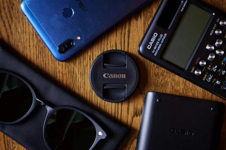 several electronic devices on a table, including a camera and a cellphone