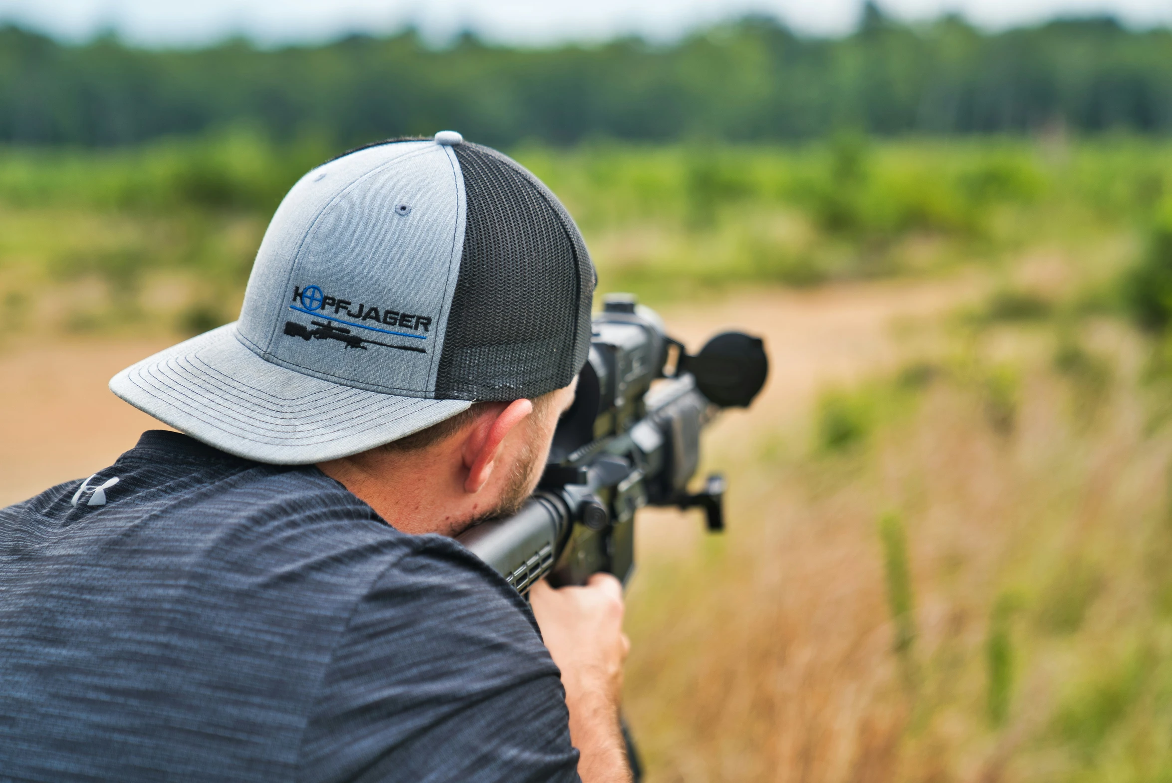 a man with a hat is taking aim in a field