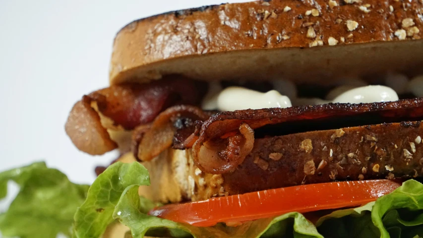 an open faced sandwich with bacon, onions, and lettuce