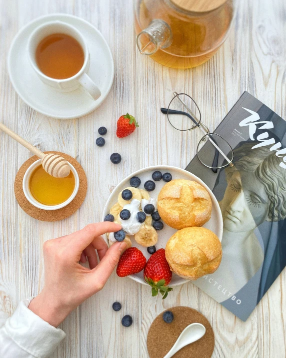 person grabbing a cookie from a plate filled with blueberries, berries and cream