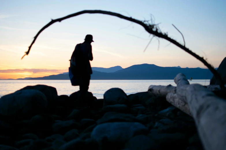 there is a man standing on rocks with the sun set