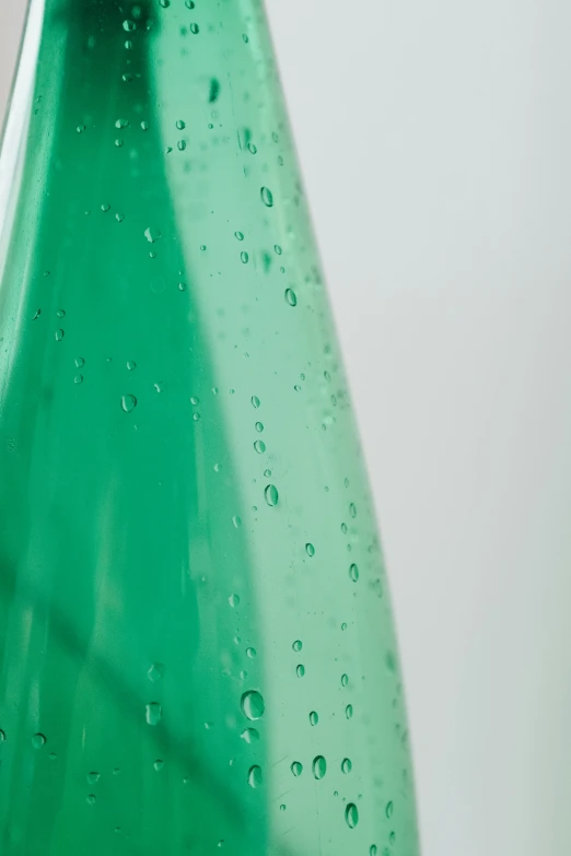 close up of the green bottle of water with drops on it