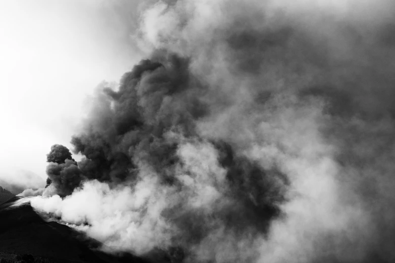 black and white po of smoke rising from mountains