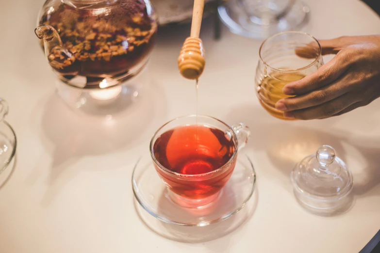 two people pouring liquid into cups on a table