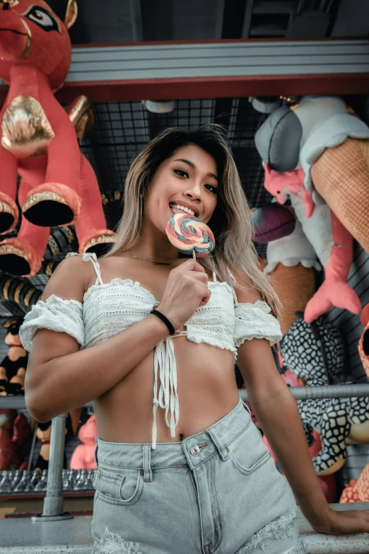 a woman in jeans eating a donut near colorful objects