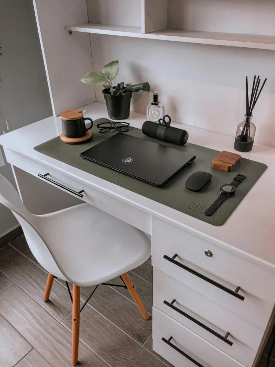 a white desk with several office supplies and a laptop on it