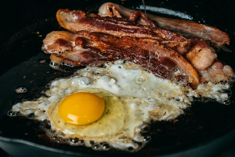 two eggs, bacon and cheese cooking in a set