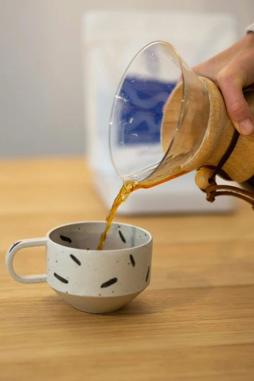 someone pours coffee from a jug into a cup