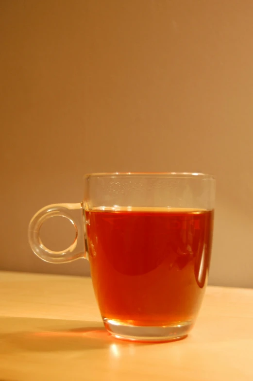 a glass cup with red liquid sitting on a table