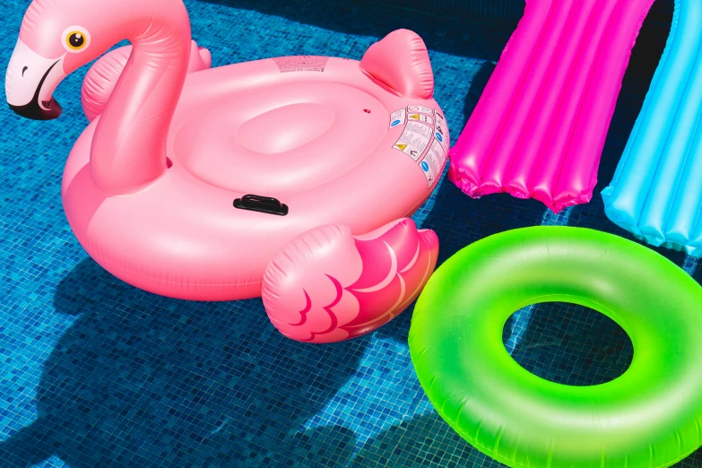 several swim floats and rings around an inflatable flamingo