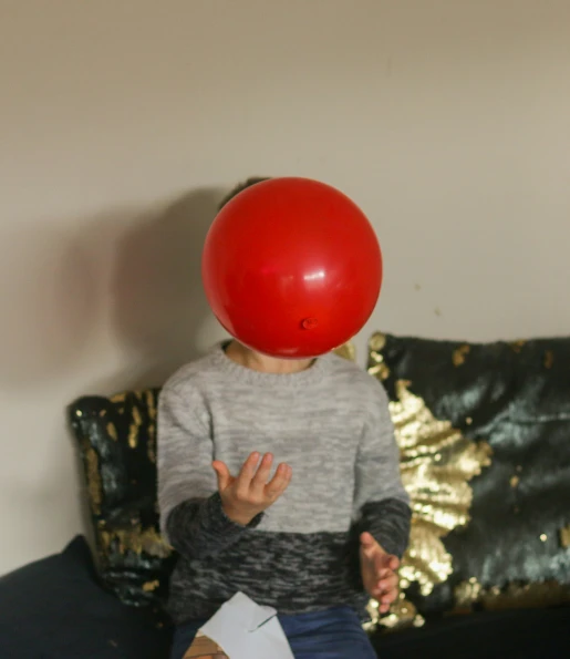 a person sitting on a couch with a red balloon on their head