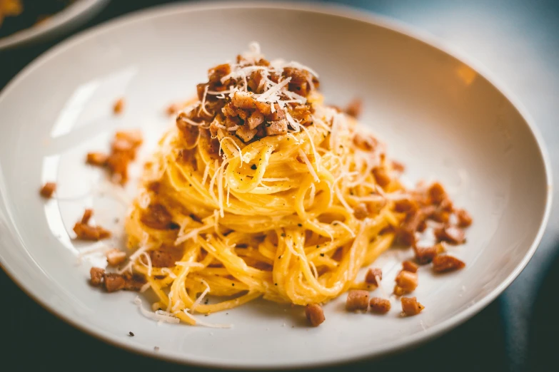 a white plate topped with noodles covered in grated bacon