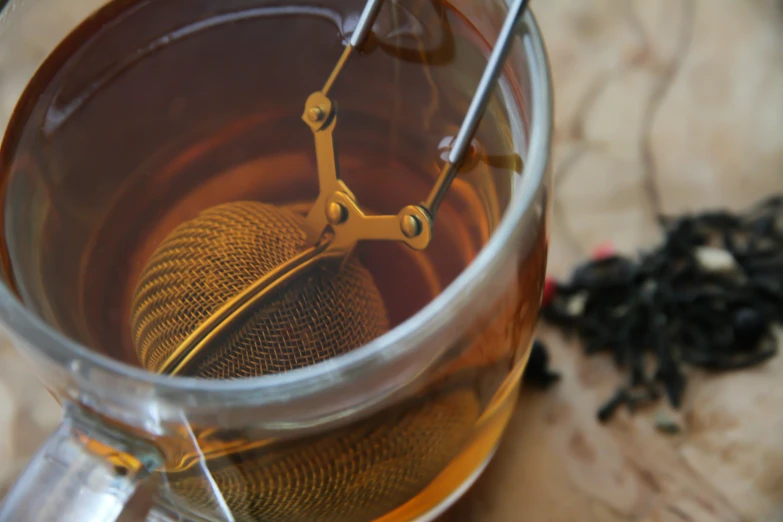 a close up of a clear tea mug with a black tea